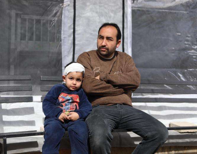 A man and his son sit outside an MSF clinic in Gaza, Palestine. 