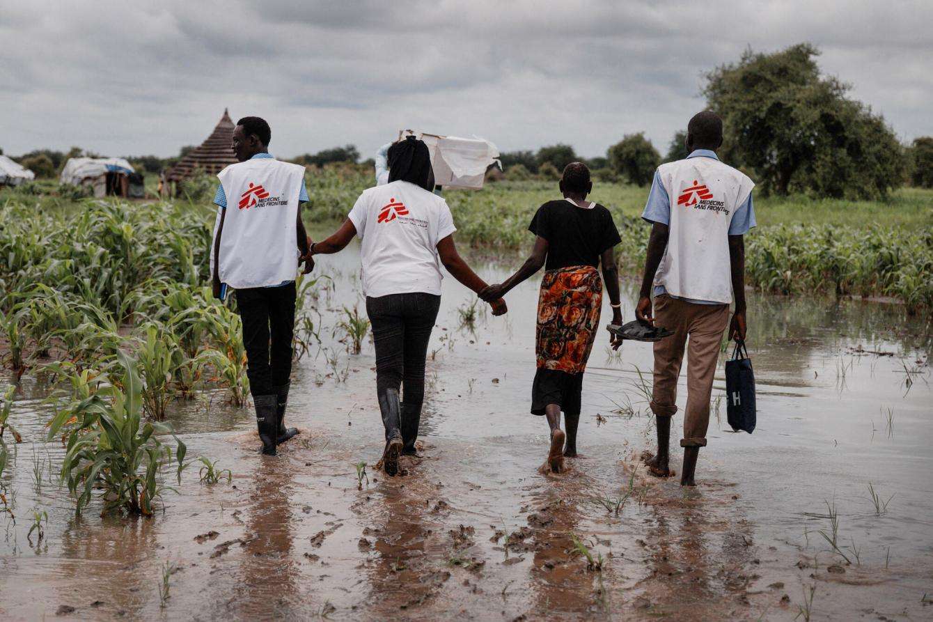MSF staff members walk across a flooded area in South Sudan